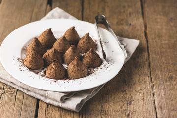 Homemade Chocolate Truffles With Cocoa Powder on a White Plate Old Wooden Background Tasty Candy Copy Space