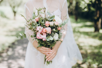 bride in white dress holds wedding bouquet