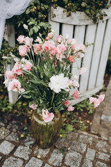 arrangement of white and pink flowers in a vase on a stone walkway