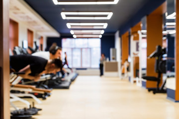 Blurred interior of modern gym with people exercising on machines