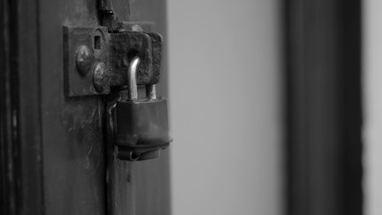 A locked padlock on the door - black and white