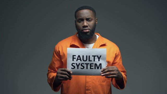 African-american male prisoner holding Faulty system sign in cell, human rights