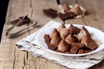 Fototapeta na wymiar Homemade Chocolate Truffles With Cocoa Powder on a White Plate Old Wooden Background Tasty Candy Horizontal