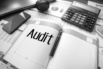 Business accessories, smartphone calculator, laptop, reports and diary with text Audit