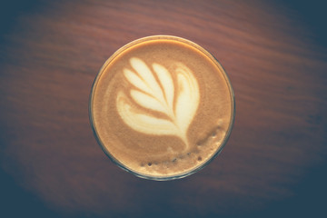 Cup of latte or cappuccino coffee with latte art on a wooden table