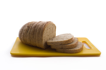 Fresh baked whole grain bread and sliced bread on plastic cutting board isolated on a white background.