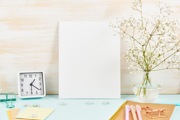 Mockup with blank white frame on blue table against wooden wall, alarm, flower in vaze