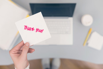 Woman clerk in the office holding paper sticker with the word: Thank you! concept
