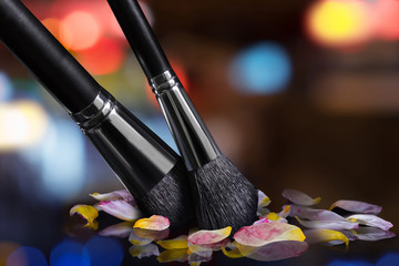 Professional brushes for a make-up and petals of tulips, close up on an indistinct color background.