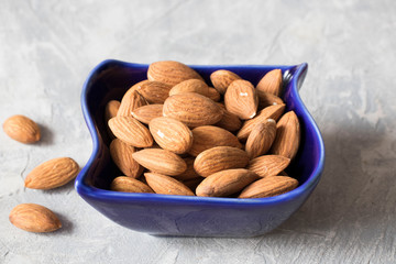 almonds in a blue bowl on the table, healthy food concept