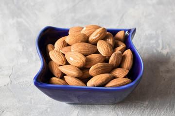 almonds in a blue bowl on the table, healthy food concept
