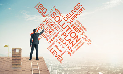 Young businessman standing on house roof and writing leadership 