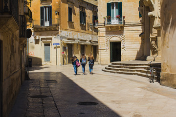 Fototapeta premium LECCE, ITALY APRIL 23, 2018: Three young girls walking to school, daily real modern life in historic town.