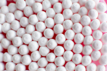Closeup view from above on round pack of cotton buds on pink background