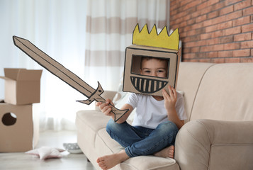 Cute little boy wearing cardboard armor in living room