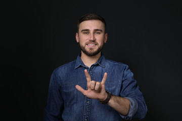 Man showing I LOVE YOU gesture in sign language on black background
