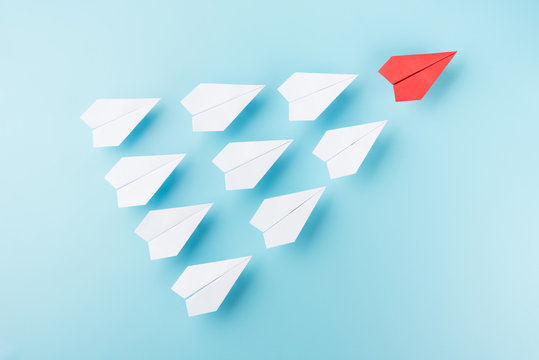 Group of white paper plane and one red plane isolated on blue background business leader teamwork growth concept photo object design