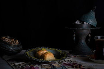 Traditional Arabic/ Turkish dessert baklava with pistachios, and tea, turkish delight dark background with authentic decoration