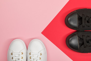 Black canvas shoes and white sneakers on red and pink background. Flat lay