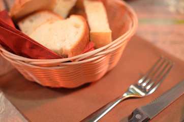 cutlary and a basket of breads on a dining table