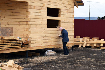 Fototapeta premium worker on construction site. Construction of wooden houses. Low-rise village.