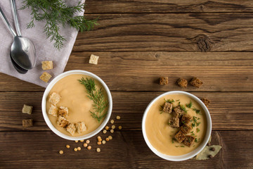 pea soup with croutons and greens on a wooden background