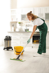 Professional janitor cleaning floor with mop in kitchen