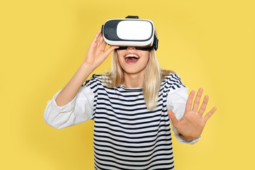 Emotional woman playing video games with virtual reality headset on color background
