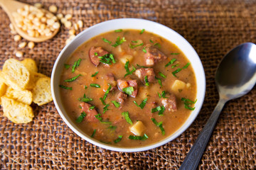 Peas soup with meat, smoked sausage and croutons. Selective focus, close-up.
