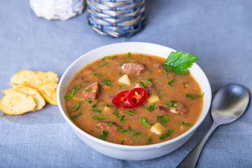 Peas soup with meat, smoked sausage and croutons. Selective focus, close-up.