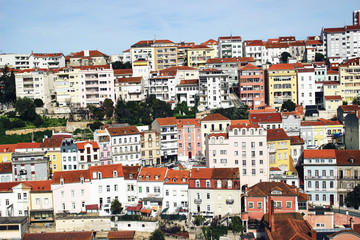Panorama of Coimbra town, former medieval capital of Portugal. View of colorful houses and roof tops over blue sky. European travel concept.