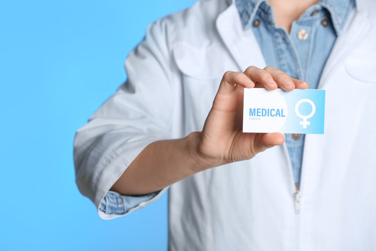 Doctor holding medical business card on color background, closeup. Women's health service