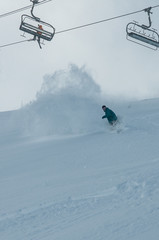 A snowboarder making a powder turn on a piste covered with fresh snow. Avoriaz, France