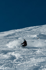 A snowboarder making a powder turn on a piste covered with fresh snow on a sunny morning. Avoriaz, France