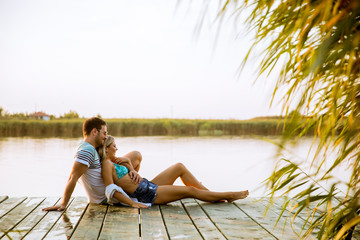 Loving couple sitting on the pier on lake