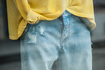 closeup of worm blue jeans and yellow pullover on a mannequin in a fashion store showroom for women