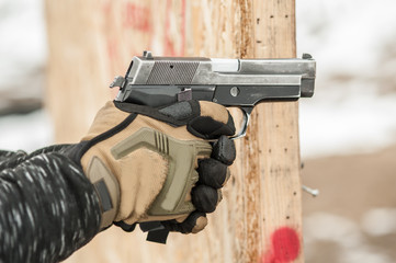 Close-up detail view of hands in gloves holding gun