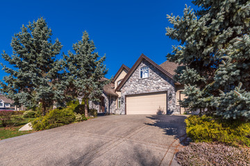 Beautiful exterior of newly built luxury home. Yard with green grass and walkway lead to front entrance.