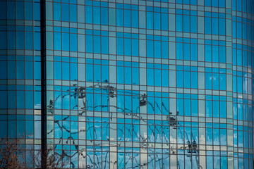 ferris wheel reflected in the mirrored windows of the building