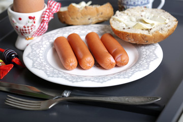 Boiled sausages, egg and bread slice with butter for breakfast