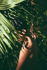 Portrait conceitual of young and beautiful man with dark shades in tropical leaves / stylish hipster man with palm leaf embracing. boy portrait with natural herb, boho sensual. romantic moment. rustic