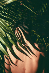 Portrait conceitual of young and beautiful man with dark shades in tropical leaves / stylish hipster man with palm leaf embracing. boy portrait with natural herb, boho sensual. romantic moment. rustic