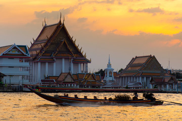 Obraz premium Tourist long trail boat is running through the temple during sunset in Bangkok.