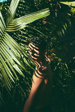 Portrait conceitual of young and beautiful man with dark shades in tropical leaves / stylish hipster man with palm leaf embracing. boy portrait with natural herb, boho sensual. romantic moment. rustic