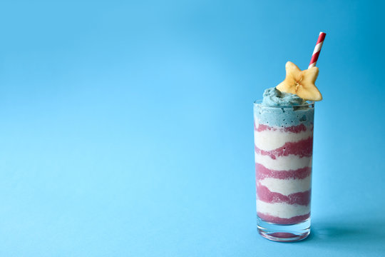 Patriotic Smoothie Glasses With Blue Spirulina, Strawberry And Vanilla Smoothies On Blue Background