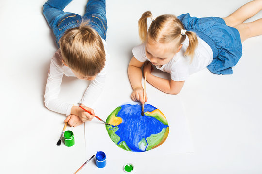 Ecology concept with two prety little kids painting earth on white background