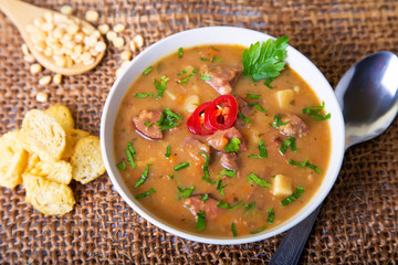 Peas soup with meat, smoked sausage and croutons. Selective focus, close-up.