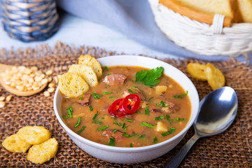 Peas soup with meat, smoked sausage and croutons. Selective focus, close-up.
