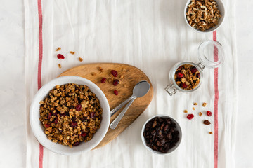 Dieting. Healthy food. Bowl of homemade granola with nuts and fruits on white linen background. Top view, copy space