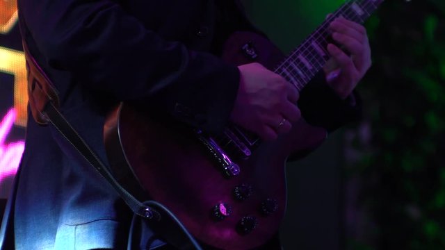 Guitarist at the concert played on dark cherry electric guitar shape Les Paul